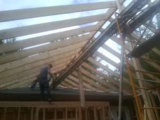 Rafters going up over a new addition with a worker on the wall in Fremont